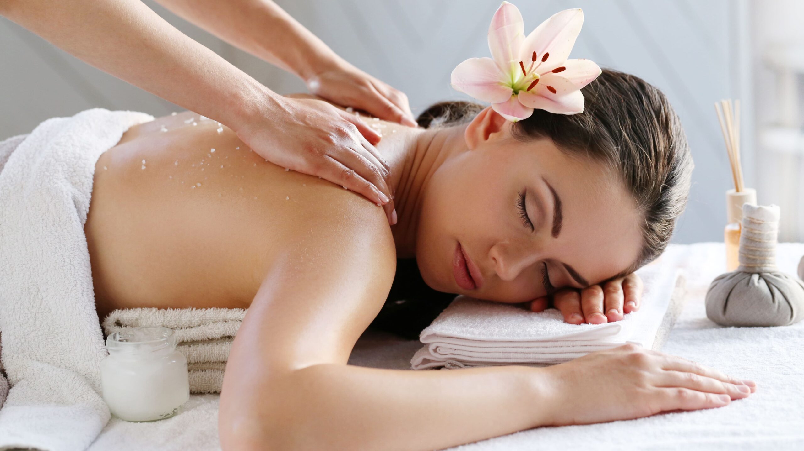 Woman lying on massage table while receiving a relaxing spa massage in a bright and peaceful treatment room